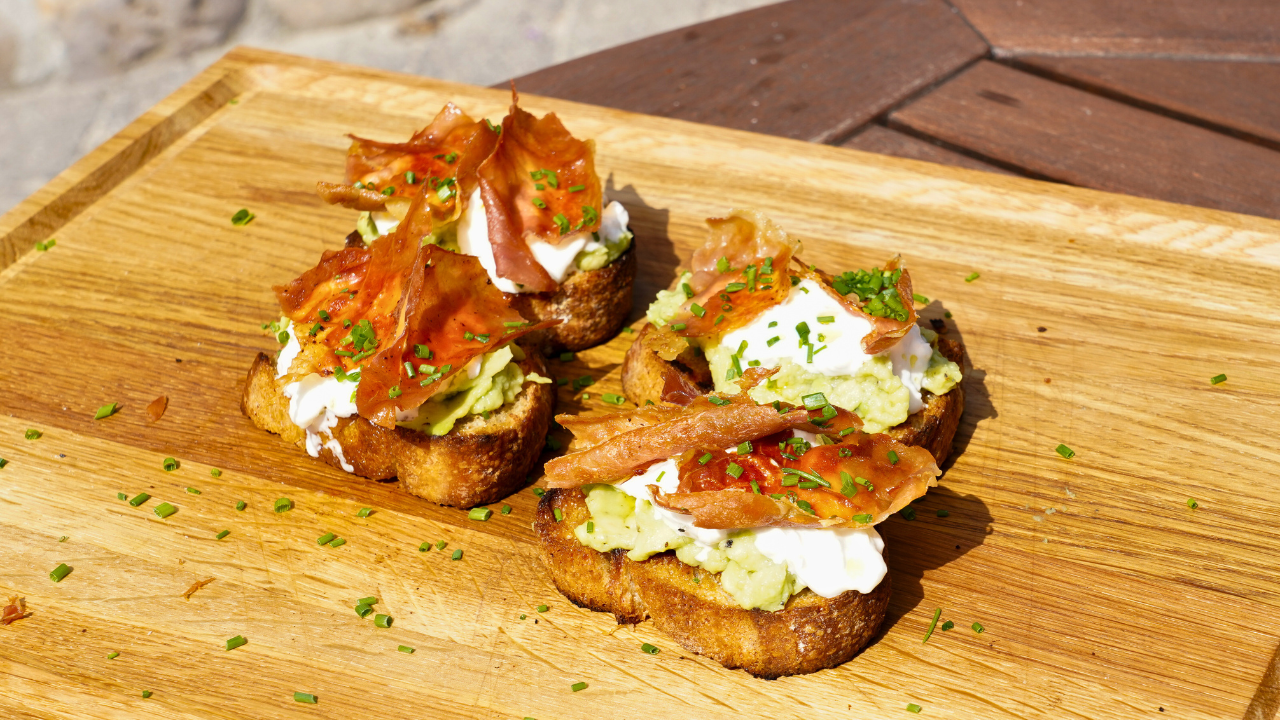 Bruschetta med avocadochiliolie burrata og sprød serranoskine anrettet på skærebræt 