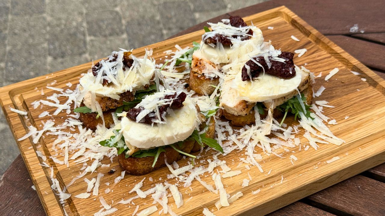 Bruschetta med kylling pesto og soltørrede tomater anrettet på skærebræt i egetræ