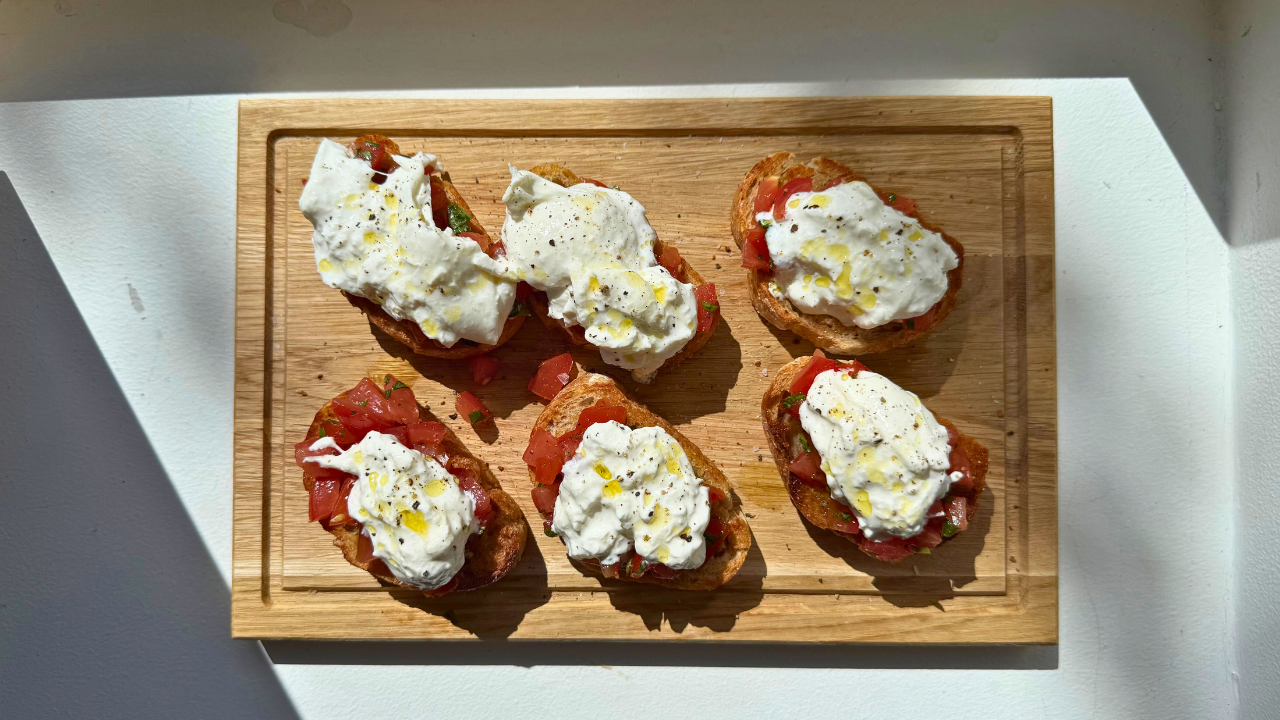 Bruschetta med ricotta tomat og frisk basilikum anrettet på skærebræt
