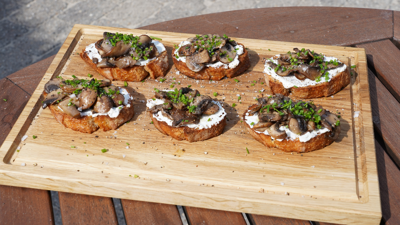 Anretning på skærebræt af lækre bruschetta med svampe hvidløg og ricotta