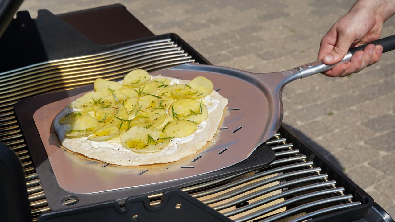 Kartoffelpizza bagning på bagestål på grill 