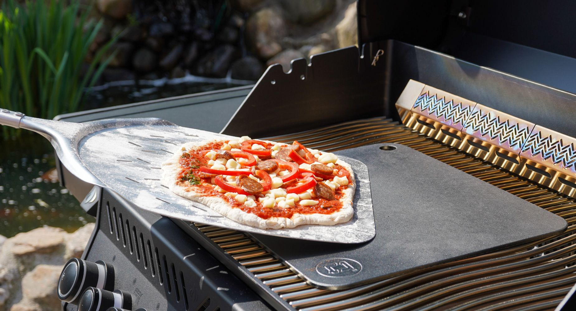 Pizzaspsde med fast håndtag lægger pizza på bagestål på grill 