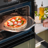 Pizzaspade med pizza på i ovn