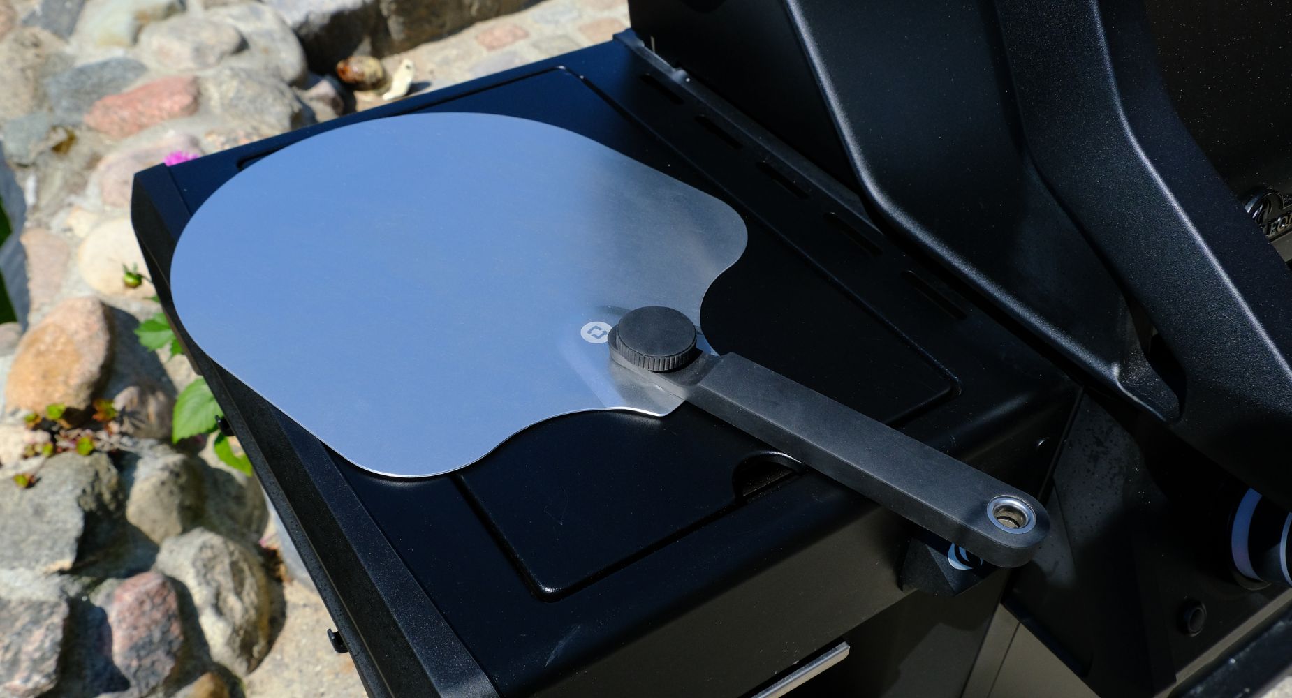 Pizzaspade med foldbart håndtag liggende ved siden af grill 