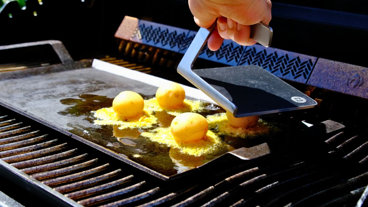 kartofler smashes på stegeplade på grillen med smasher i rustfrit stål