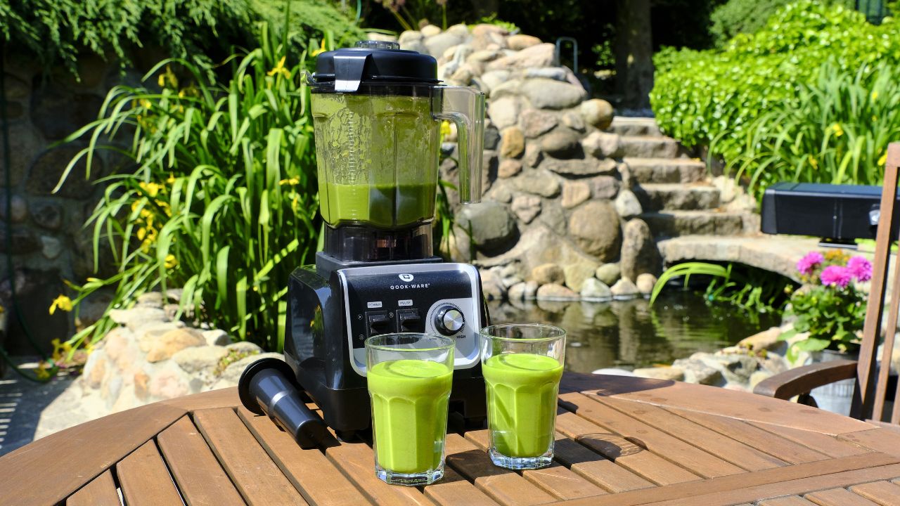 Grøn energibooster smoothie anrettet i glas foran blender 