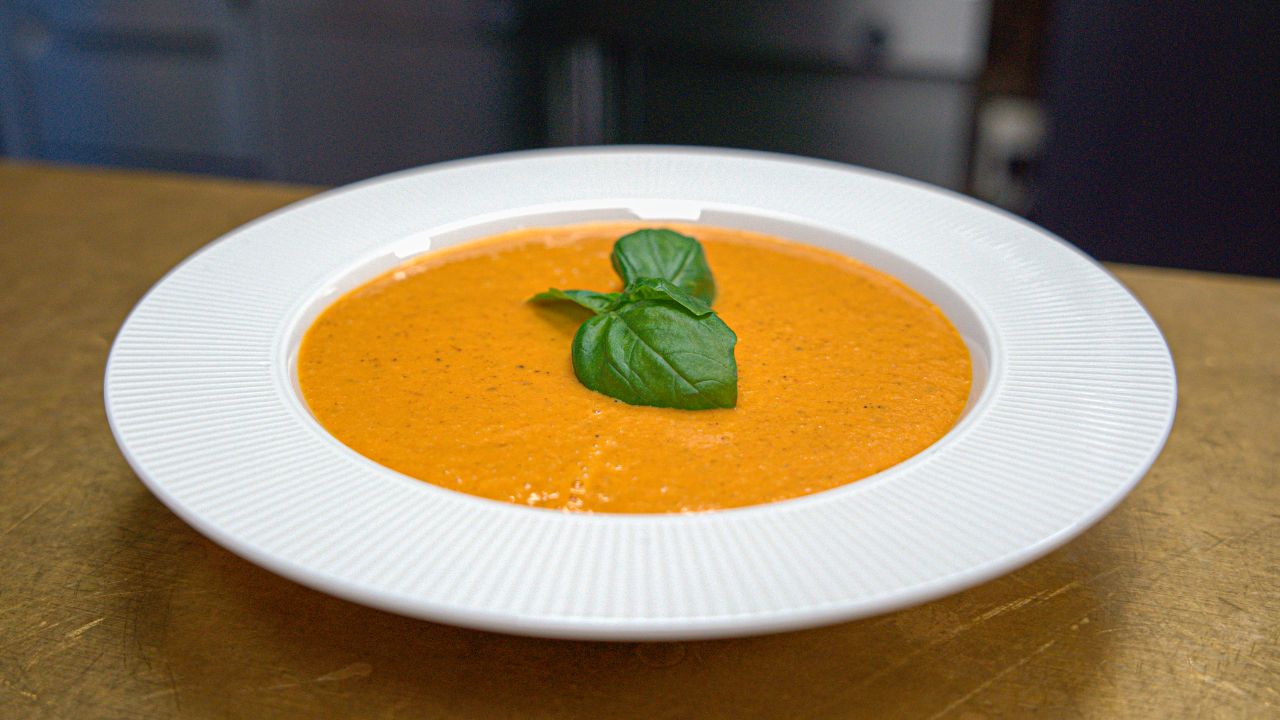 Tomatsuppe anrettet med basilikum i en dyb tallerken 